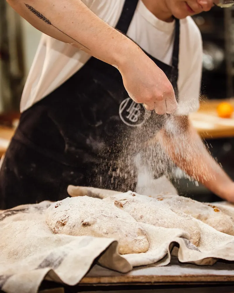 Flour being dusted over proofing loaves