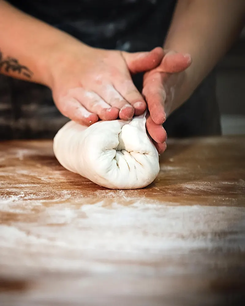 A baker’s hands shaping a swirl of dough