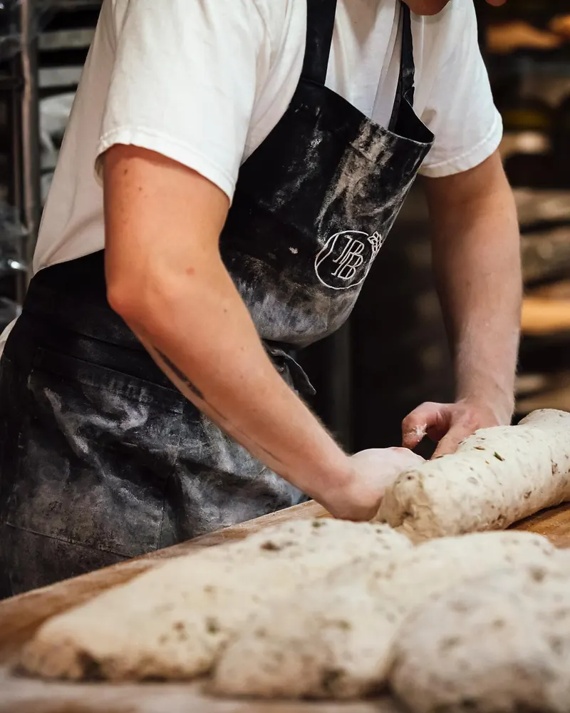 A baker in the Palma Bread apron shaping dough